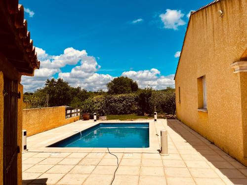 - une piscine dans une cour à côté d'un bâtiment dans l'établissement Spacieuse Maison de Vacance Villa Les Lavandins, à Puisserguier
