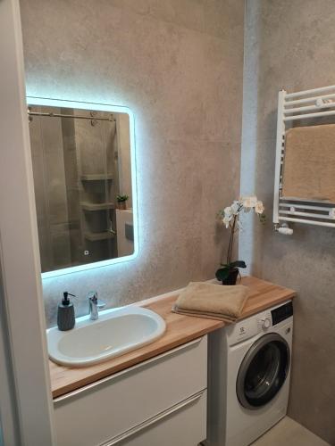 a bathroom with a sink and a washing machine at Apartament rodzinny 47, 150 m od plaży, basen, plac zabaw, darmowy parking! in Sianozety
