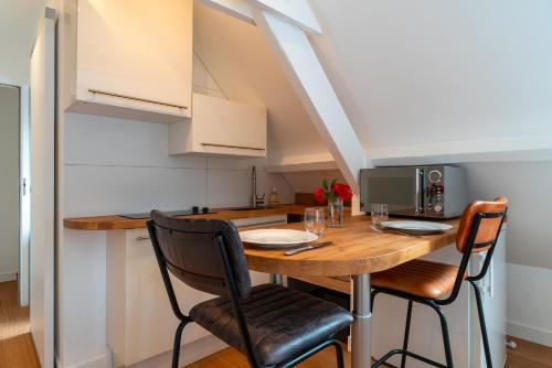 une cuisine et une salle à manger avec une table et des chaises en bois dans l'établissement La Timonerie - Appt climatisé à Bénodet vue mer, à Bénodet