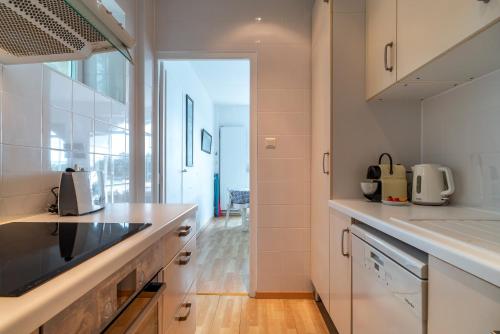 une cuisine avec des appareils blancs et une grande fenêtre dans l'établissement Le Savenn - Appt vue mer 4p à Bénodet, à Bénodet