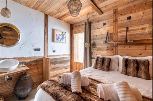 a bedroom with wooden walls and a bed and a sink at Chalet Le Perchoir, Spa, Sauna, sur les pistes in Villard-Reculas
