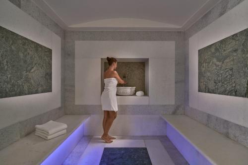 a woman standing in a bath tub in a room at Ios Palace Hotel & Spa in Mylopotas