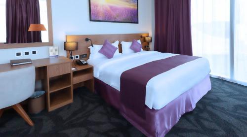 a hotel room with a large bed and a desk at Park Regis Business Bay in Dubai