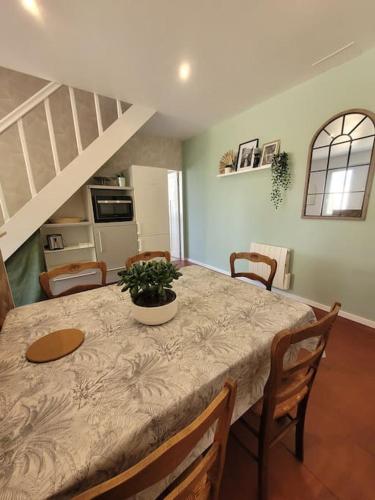 une salle à manger avec une table, des chaises et un escalier dans l'établissement La petite maison, à Le Trait