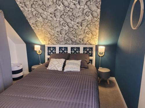 une chambre avec un grand lit avec un tableau au mur dans l'établissement La petite maison, à Le Trait