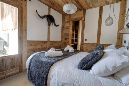 a bedroom with a large white bed with wooden walls at Chalet Le Perchoir, Spa, Sauna, sur les pistes in Villard-Reculas