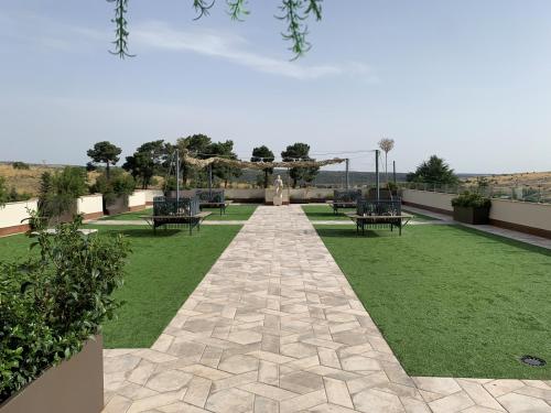 a garden with benches and a pathway with grass at Hotel Sercotel Cuatro Postes in Avila