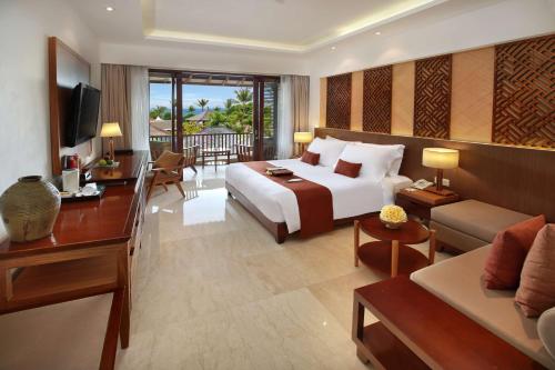 a hotel room with a bed and a living room at Bali Niksoma Boutique Beach Resort in Legian