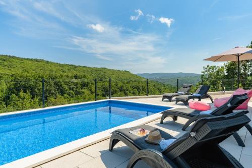 a swimming pool with lounge chairs and an umbrella at Villa Manola by Briskva in Labin