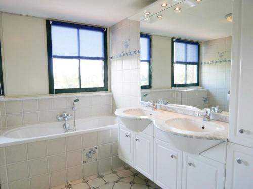 a bathroom with two sinks and a tub and a mirror at Buitenplaats 78 in Callantsoog