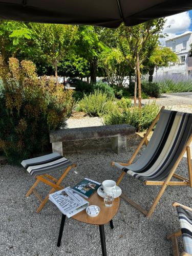 two chairs and a table with a book and a cup at Logis Hotel Le Richelieu - Royan Atlantique in Saujon