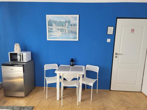 a table and chairs in a room with a blue wall at Pokoje Gościnne Galeon w Darłówku in Darłowo
