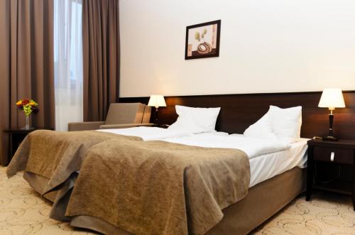 a hotel room with two beds and a chair at Hotel Kudowa Manufaktura Relaksu in Kudowa-Zdrój