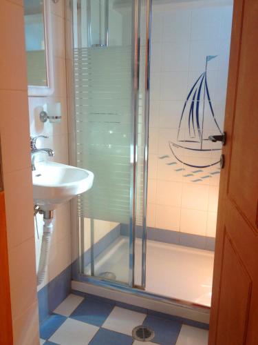a bathroom with a sink and a shower with a boat on the wall at Mantraki Hotel Apartments in Agios Nikolaos