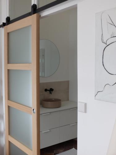 La salle de bains est pourvue d'une porte en verre et d'un lavabo. dans l'établissement L'artiste, à Orléans