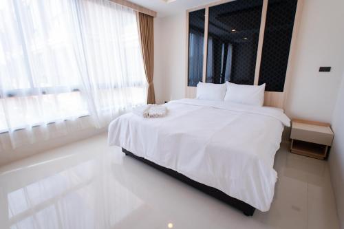 a white bed in a room with a large window at โรงแรมกัญธิญา การ์เด้น Kanthiya garden hotel in Ban Si Muang Mai