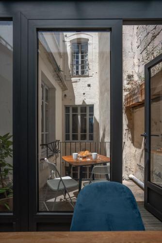 une porte en verre avec une table et une chaise sur un balcon dans l'établissement Le Duplex, à Avignon
