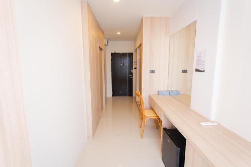 a hallway with a table and a chair in a room at โรงแรมกัญธิญา การ์เด้น Kanthiya garden hotel in Ban Si Muang Mai