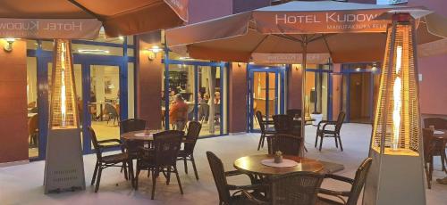 a restaurant with tables and chairs and an umbrella at Hotel Kudowa Manufaktura Relaksu in Kudowa-Zdrój