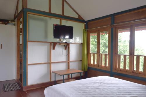 a bedroom with a bed and a tv on a wall at Avadale Wayanad - Stag Groups Not Allowed in Kalpetta