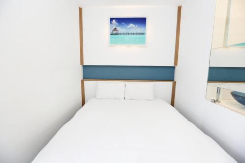 a bed in a room with a picture on the wall at Hamdeok Beach Stay Jeju in Jeju