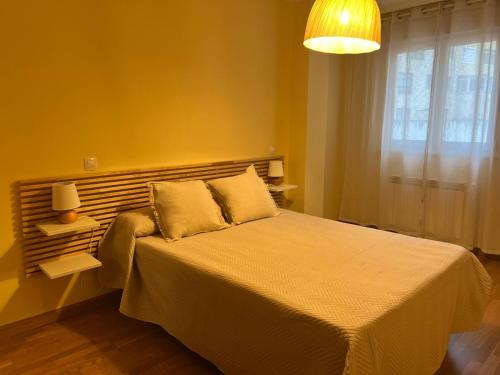 a bedroom with a large bed with a yellow wall at Apartamentos Terraza playa II in Foz