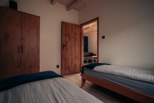 a bedroom with two beds and a door to a room at Domki Dolina Roztocza in Zwierzyniec