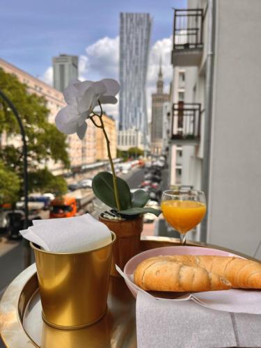 a table with a plate of bread and a glass of orange juice at Final 1room Condo WarszawaCenter in Warsaw