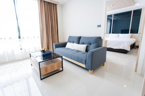 a living room with a blue couch and a bed at โรงแรมกัญธิญา การ์เด้น Kanthiya garden hotel in Ban Si Muang Mai