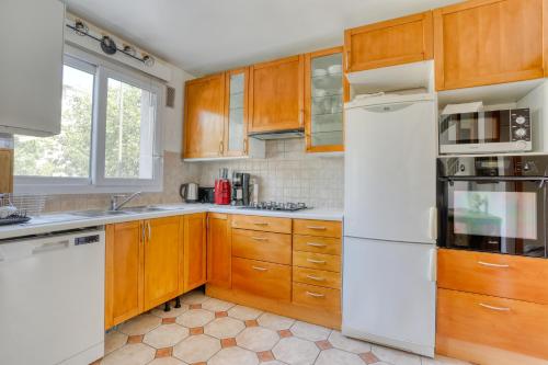 une cuisine avec des armoires en bois et un réfrigérateur blanc dans l'établissement Cette Maison est la Vôtre, à Suresnes