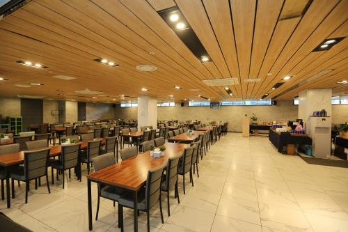 a restaurant with wooden ceilings and tables and chairs at Hamdeok Beach Stay Jeju in Jeju