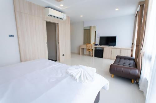 a hotel room with a white bed and a chair at โรงแรมกัญธิญา การ์เด้น Kanthiya garden hotel in Ban Si Muang Mai