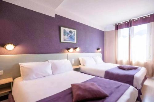 - 2 lits dans une chambre d'hôtel aux murs violets dans l'établissement Hôtel Christina Lourdes, à Lourdes