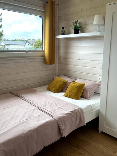 a bed with two pillows in a room with a window at Słoneczna Gąska in Gąski