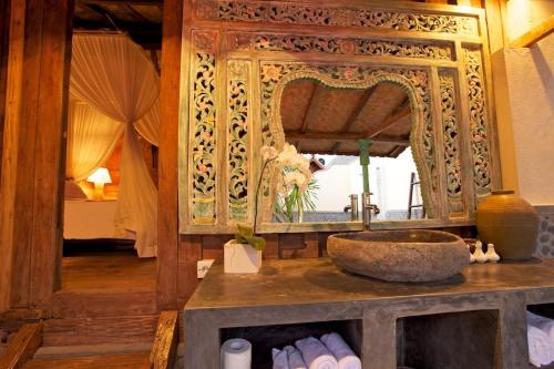 ein Bad mit einem Waschbecken und einem Spiegel in der Unterkunft The Kampung in Amed