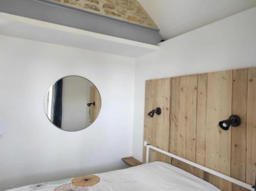- une chambre avec une tête de lit en bois et un miroir dans l'établissement Gite Les'Couves, à Colombiers