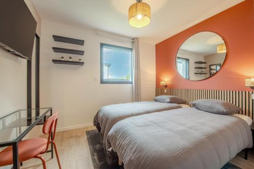 two beds in a room with a mirror at Maison Simone - Belle Maison pour 6 avec Jacuzzi in Lesneven