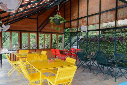 a restaurant with yellow tables and colorful chairs at Avadale Wayanad - Stag Groups Not Allowed in Kalpetta