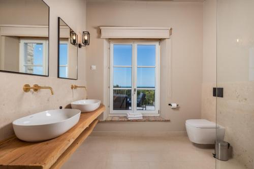 a bathroom with two white sinks and a window at Villa Plava with Panoramic Seaview and big pool in Bale