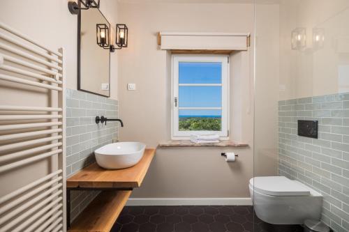 a bathroom with a sink and a toilet and a window at Villa Plava with Panoramic Seaview and big pool in Bale