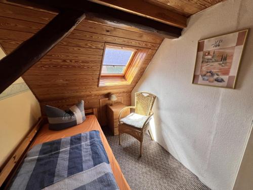 a small attic room with a bed and a chair at Zum ehemaligen Kaffeekännchen in Funfseen