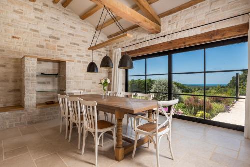 a dining room with a wooden table and chairs at Villa Plava with Panoramic Seaview and big pool in Bale