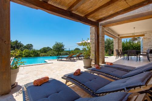 a patio with blue cushioned chairs and a swimming pool at Villa Plava with Panoramic Seaview and big pool in Bale