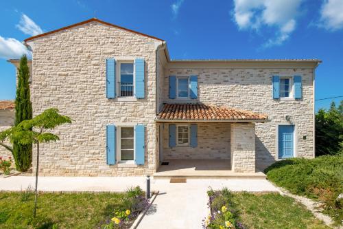 a large stone house with blue shutters on it at Villa Plava with Panoramic Seaview and big pool in Bale