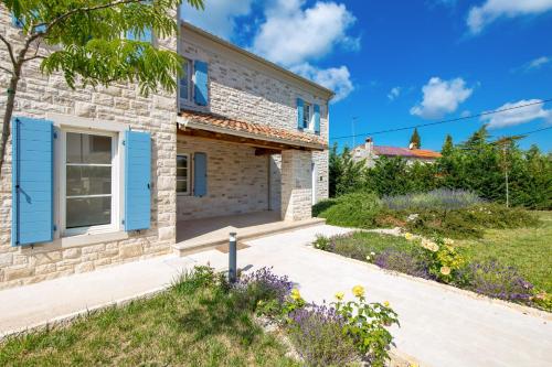a stone house with blue shutters and a garden at Villa Plava with Panoramic Seaview and big pool in Bale