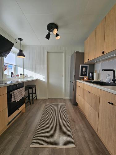 a kitchen with wooden cabinets and a stainless steel refrigerator at Bright and modern apartment with beautiful view in Hammerfest