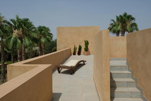 un patio con una panchina e delle palme di Villa BELYA a Marrakech
