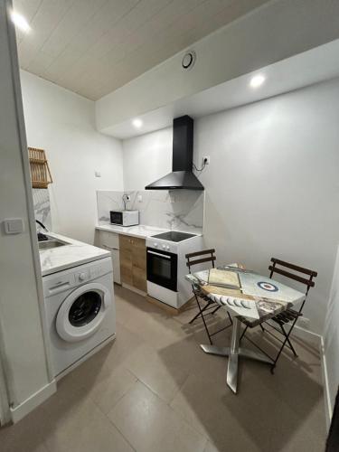 une cuisine avec un lave-linge, une table et des chaises dans l'établissement petit Muguet, à Avignon