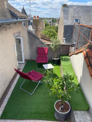 un patio d'appartement avec deux chaises et de l'herbe verte dans l'établissement So British ! Appart atypique et sa petite terrasse, à Poitiers