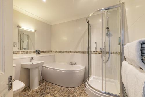 a bathroom with a tub and a sink and a shower at The Palace Hotel in Paignton